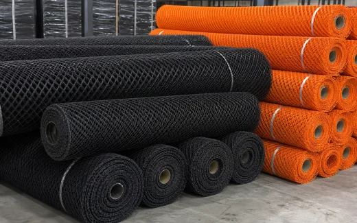 Black HDPE mesh rolls and orange safety mesh rolls in a warehouse