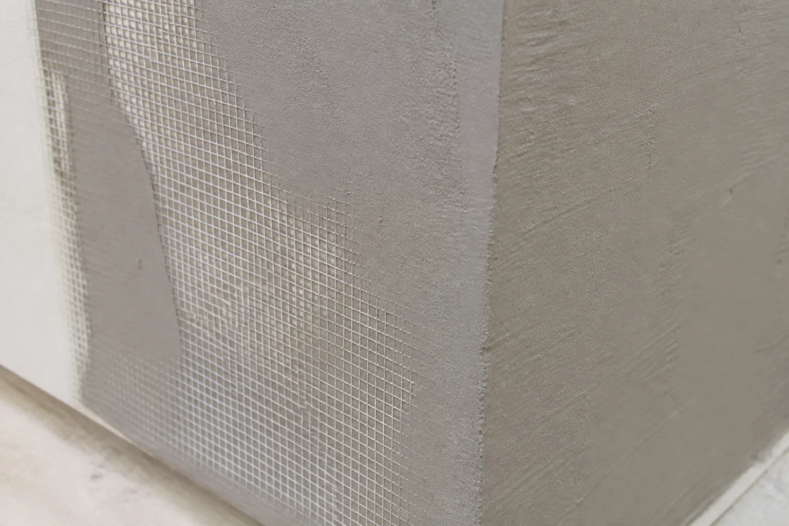 Fiberglass mesh embedded in a wall base-coat layer at an exterior corner