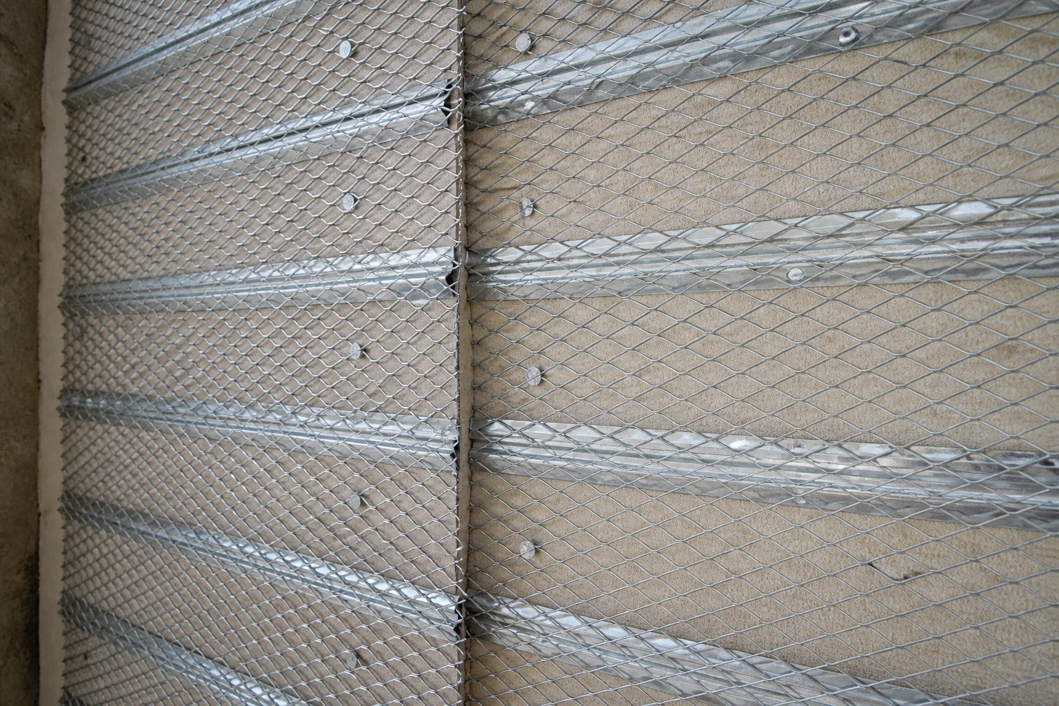 Galvanized rib lath fastened over a wall substrate before plaster application